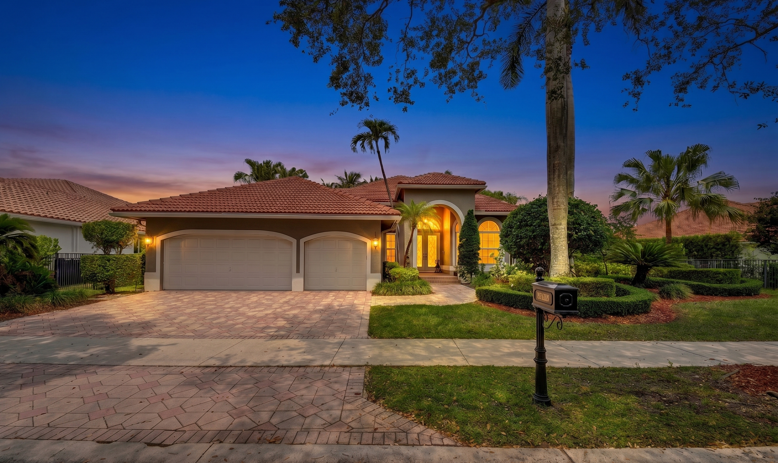 Twilight exterior of a single story South Florida home with barrel tile roof three car garage circular driveway and mature palm landscaping representative of the architecture inside Maple Island the gated sub community within The Islands of Weston FL where 1640 Island Way is hosting an open house Sunday May 24 2026