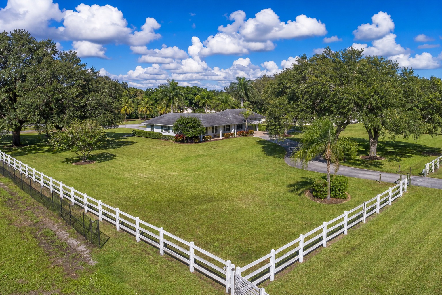 Davie Florida property with white fencing marking the boundary line of an acreage lot with palm trees and a single family home, representing a property survey in 2026