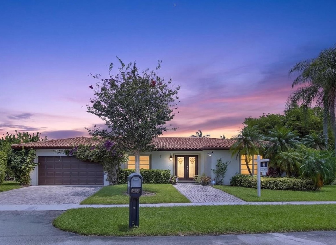 Twilight exterior of 16641 Royal Poinciana Dr, a single story 1977 home in the Bonaventure Lakes section of Weston FL, showing the barrel tile roof, two car garage, paver driveway, flowering tree and mature palm landscaping, listed at ,200,000 and open for touring August 8 and 9 2026
